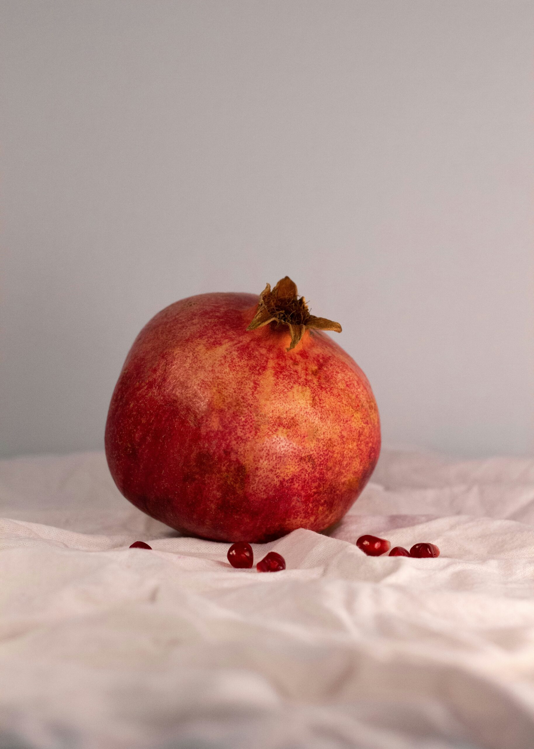 pomegranate with loose seeds on a white sheet